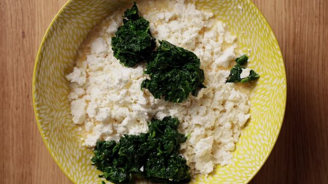 Adding Wilted Spinach To Feta Cheese Bowl Top View