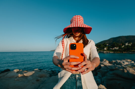woman taking photo with cellphone on the beach