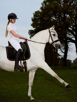 Young Woman Riding a White Horse in a Grassy Field