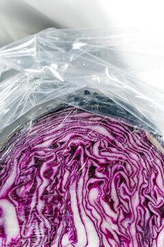 Purple Cabbage Cut in Plastic Wrap on a White Surface