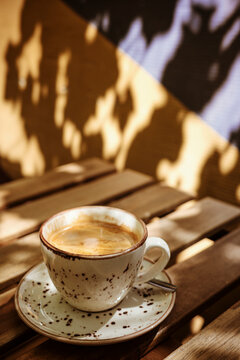 Coffee Cup on a Wooden Table With Shadows in Afternoon Light