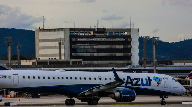Vista lateral de avi&atilde;o da Azul em movimenta&ccedil;&atilde;o operacional na pista, com luz natural e &aacute;rea gramada compondo a cena aeroportu&aacute;ria.