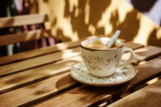 Coffee Cup on a Wooden Table With Shadows in Afternoon Light