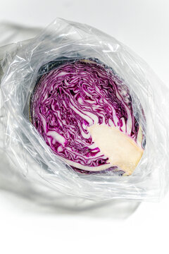 Purple Cabbage Cut in Plastic Wrap on a White Surface