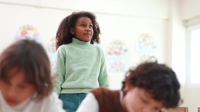 Confident African American girl standing in classroom smiling. Elementary school student giving a presentation or answering a question during lesson.
