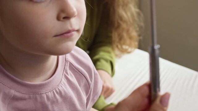 Tilt up close up of Caucasian child sitting with mother during medical checkup while pediatrician performing eye tracking test using neurological hammer. Perfect for pediatric healthcare marketing