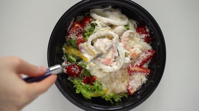 Delicious seafood caesar salad with shrimp and calamari in a bowl, isolated on a white background and ready for takeaway delivery