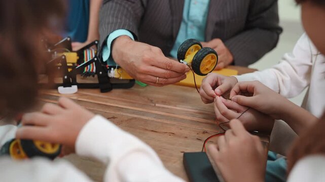 Close up of diverse students and teacher hands building a robot. Teamwork and collaboration during a STEM science project in elementary school.