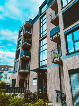 Modern residential apartment building with bicycles at entrance and minimalist contemporary architecture under cloudy blue sky