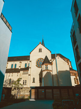 Historic church architecture and modern residential building in urban courtyard under dramatic cloudy blue sky