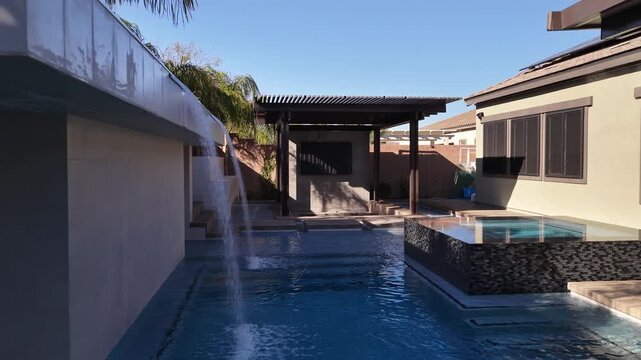 Modern luxury backyard with swimming pool hot tub and custom waterfall feature 4K