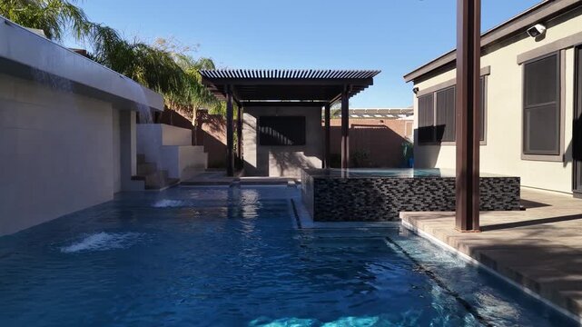 Modern luxury backyard patio with swimming pool and waterfall feature in 4K