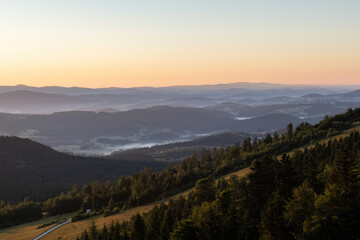 Obraz premium Golden sunrise light illuminates rolling hills and forests seen from Geisskopf in the Bavarian Forest.