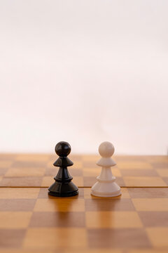 Black and white chess pawn pieces facing each other on chessboard, ordinary employees competition concept.