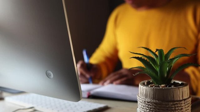 Unfocused person writing notes at a computer desk