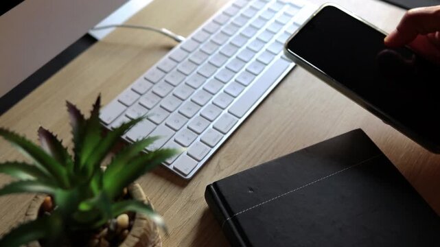 Person using smartphone on modern wooden office desk