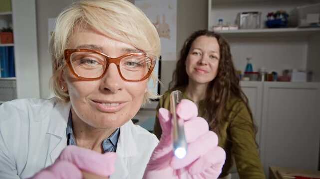 POV of middle aged Caucasian female pediatrician looking at camera, holding flashlight and tongue depressor for throat exam. Video perfect for pediatric healthcare advertising