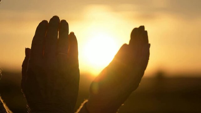 Silhouette of hands praying at sunset, spiritual connection and hope, cinematic close-up of devotion and faith