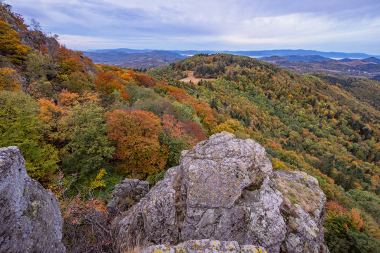 View of the autumn forest from Sitno peak in the Stiavnicke vrchy mountains with colorful foliage and rocky outcrops under a cloudy sky in Ilija, Banska Bystrica Region, Slovakia.