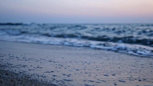 Gentle ocean waves rolling onto sandy beach at sunset, serene coastal shoreline background