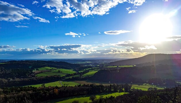 Vibrant landscape with rolling hills under a bright sunny sky and clouds