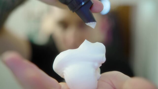 Close up of applying hair styling foam mousse on hand before styling hair. Hair care, grooming and beauty routine concept.