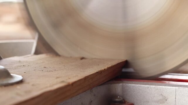 The process of sawing a wooden block with a miter saw. Close-up of the blade in operation. Working with wood, a miter saw cuts a wooden workpiece. The concept of construction and carpentry. Work
