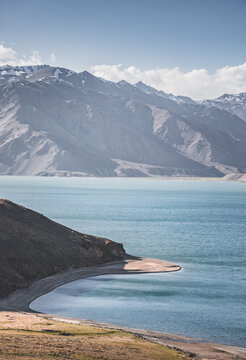 Landscape in the Pamir Mountains with a blue lake Yashilkul in the Tien Shan, a panoramic view of the highlands with snow-capped rocky peaks and the blue waters of the lake