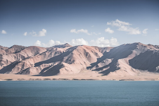 Landscape in the Pamir Mountains with a blue lake Yashilkul in the Tien Shan, a panoramic view of the highlands with snow-capped rocky peaks and the blue waters of the lake