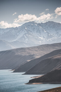 Landscape in the Pamir Mountains with a blue lake Yashilkul in the Tien Shan, a panoramic view of the highlands with snow-capped rocky peaks and the blue waters of the lake