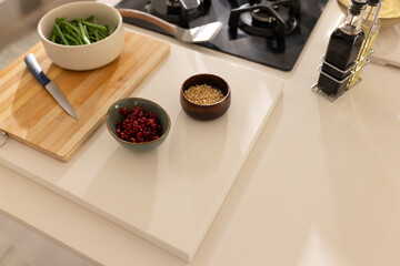 Obraz premium Wooden board, blue knife, green beans, pomegranate and pine nuts sitting near gas stove on counter