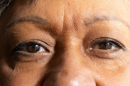 Senior African American woman showing eye close-up in studio, highlighting mascara eyeliner mole