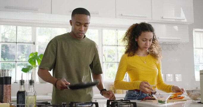 Couple preparing meal at kitchen counter, man using pepper mill and flipping pan, woman mixing bowl