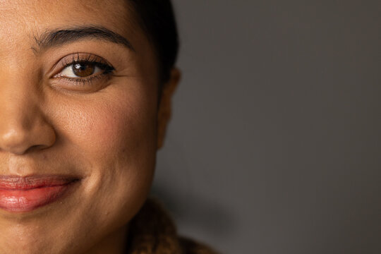 Adult African woman posing in studio showing left face with eyeliner red lipstick brown knit