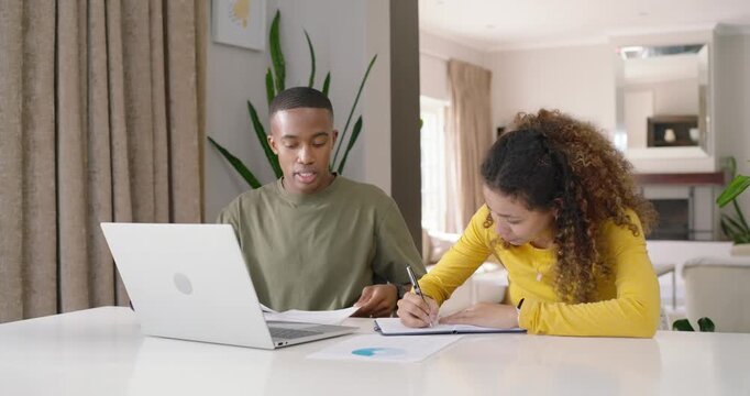 Diverse couple checking smartphone, comparing charts, verifying details and clicking laptop at home