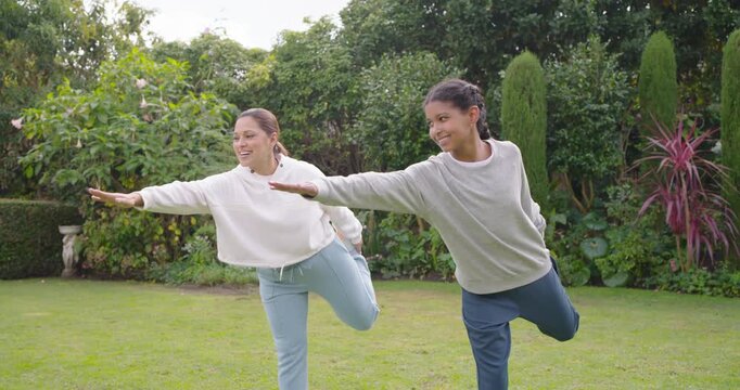 African American mom and teen after playful nudge doing balance on backyard, mother wobbling