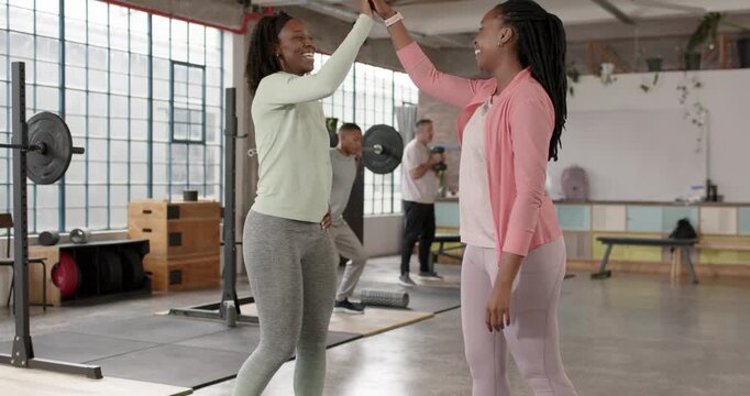 African American women greeting, mutual eye contact starting left woman high-fiving at loft barbell