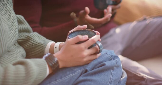 Couple sitting on couch, woman holding blue-gray mug while man speaking with dark mug, steam rising