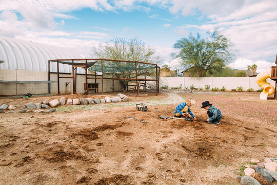 Boys Playing in Dirt with Chicken Coop in Desert Backyard