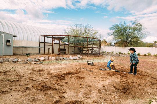Boys Playing in Dirt with Chicken Coop in Desert Backyard