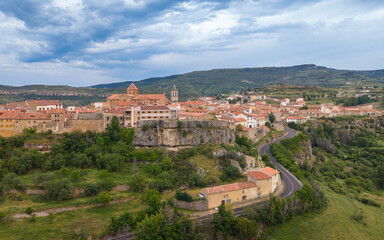 Fototapeta premium Aerial view of Cantavieja medieval town perched on limestone cliff with church towers, terracotta rooftops and winding road, Maestrazgo, Teruel, Aragon, Spain