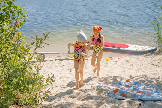 The girls are running along the shore of the lake, catching up with each other. Children have fun on vacation. Unity with nature. Family camping