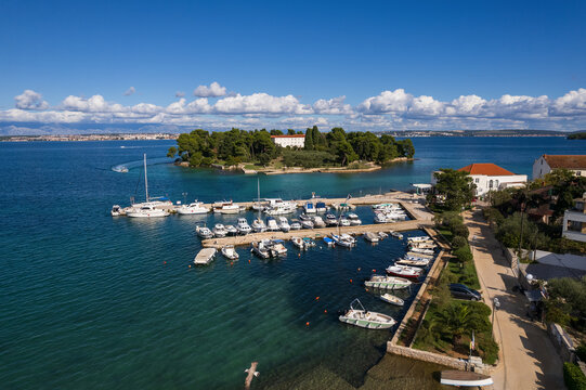 Aerial view of the small, forested Galevac island in the Adriatic sea, near Preko on Ugljan island, Croatia. Crystal clear turquoise water surrounds the historic monastery hidden in lush green trees.