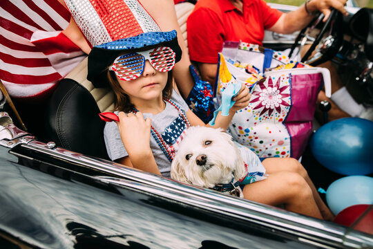 Girl riding in Fourth of July parade with dog