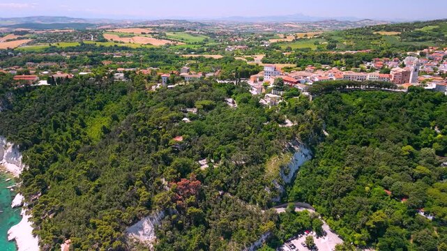 Sirolo Marche Italy 4k drone of San Michele and Urbani beach. Panoramic panning view revealing historic borgo village on white cliff with tropical turquoise sea toward Monte Conero mountain b-roll