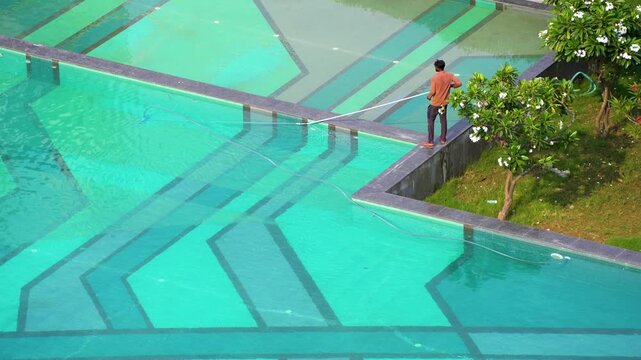 Gurgaon, Delhi, India - 11th mar'26: A maintenance worker cleaning a large swimming pool at a premium residential condominium in Gurgaon, highlighting property upkeep and leisure facilities.