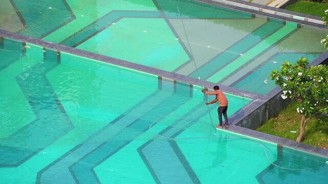 Gurgaon, Delhi, India - 11th mar'26: A maintenance worker cleaning a large swimming pool at a premium residential condominium in Gurgaon, highlighting property upkeep and leisure facilities.