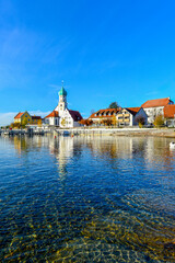 Fototapeta premium Froschperspektive auf die Halbinsel Wasserburg am Bodensee mit kristallklarem Wasser im Vordergrund