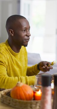 Vertical video: Man in yellow knit talking to off-frame person, lifting fork and eating at table