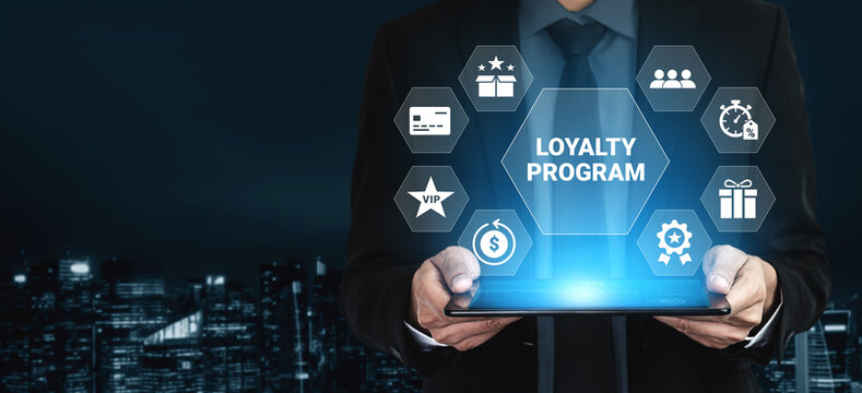 Businessman holds tablet showcasing loyalty program concept with glowing icons. Innovative visual representation of customer rewards and engagement strategies. Ledger